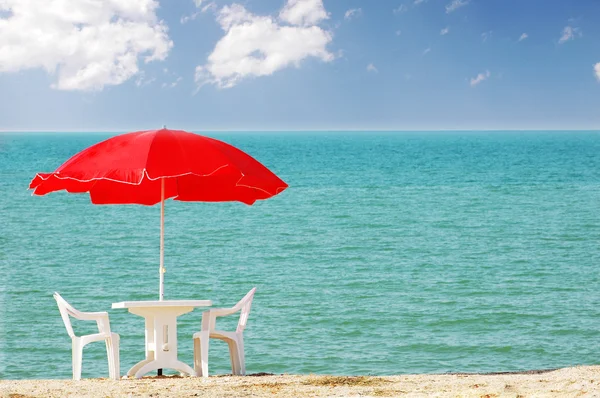 Стол, стулья и зонтик на пляже — стоковое фото