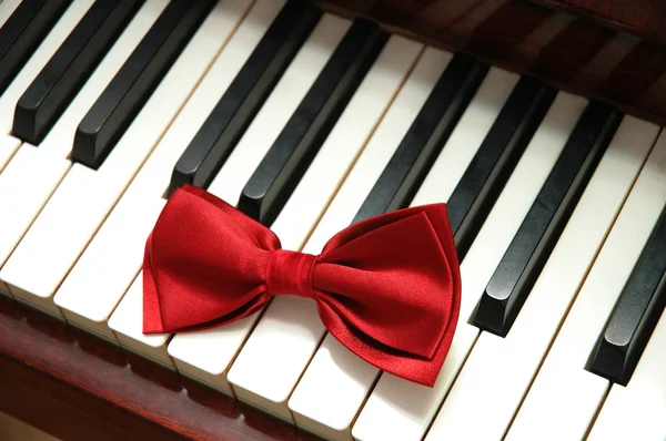 흰색 피아노 키에 빨간 나비 넥타이 — 스톡 사진
