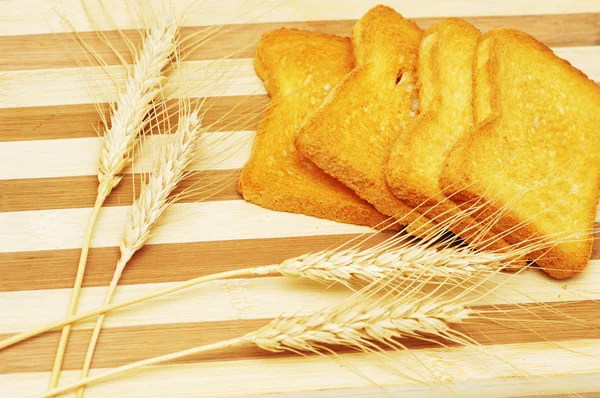 Quatro pedaços de torradas e espigas de trigo — Fotografia de Stock