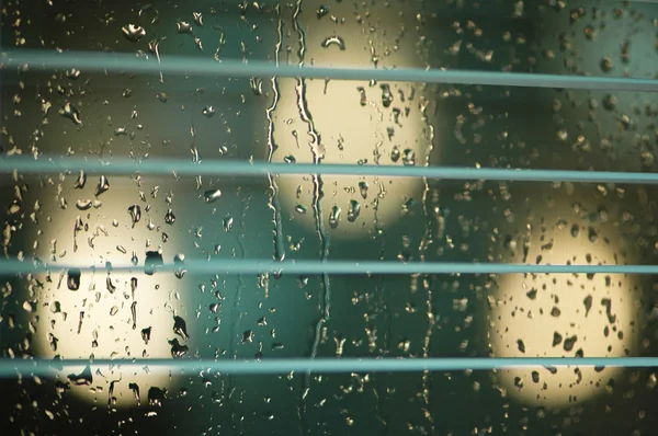 Water drops on the glass and blinds — Stock Photo, Image
