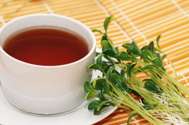 Cup of black tea and herbs on orange mat