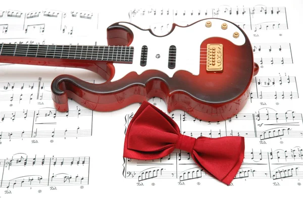 Guitarra e laço gravata sobre a folha — Fotografia de Stock