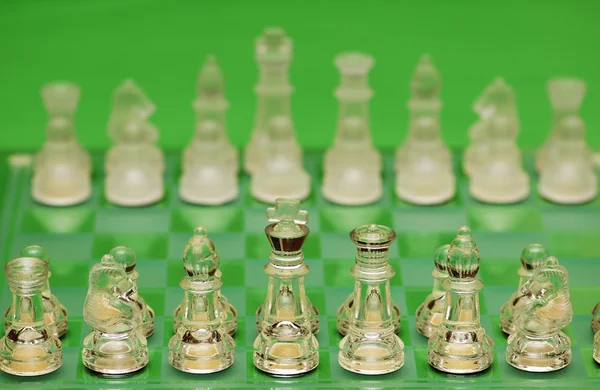 Glass chess figures against green — Stock Photo, Image