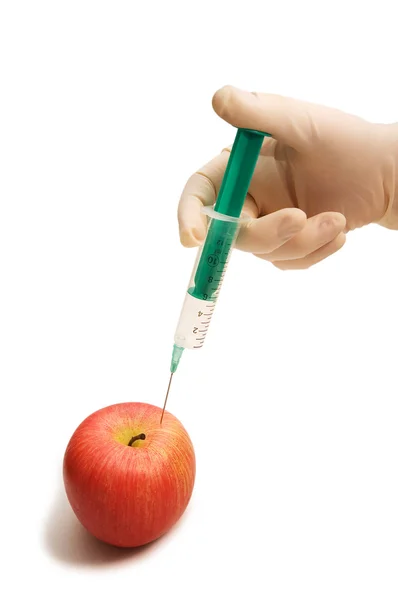 Рука со шприцем и красным яблоком — стоковое фото
