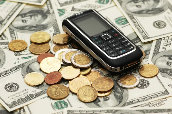 Telefone celular com moedas e dólares — Fotografia de Stock
