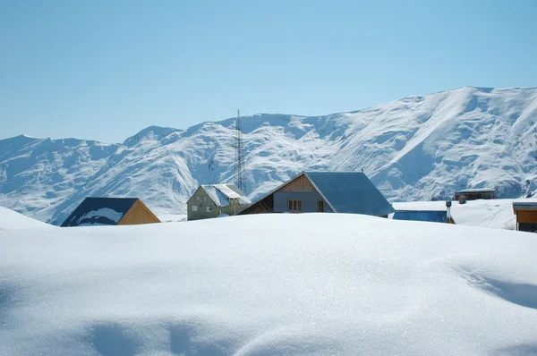 Yüksek dağlar ve kar altında evleri — Stok fotoğraf