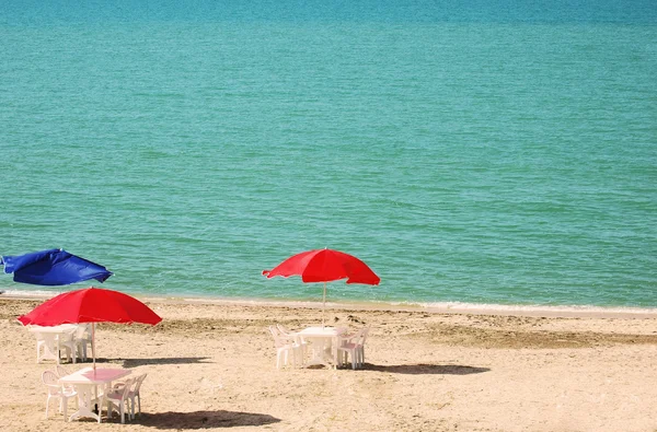 Три стола с зонтиками на пляже — стоковое фото
