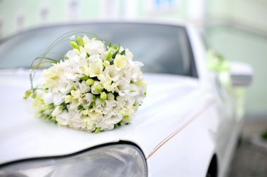 Wedding bouquet lies on the car clipart