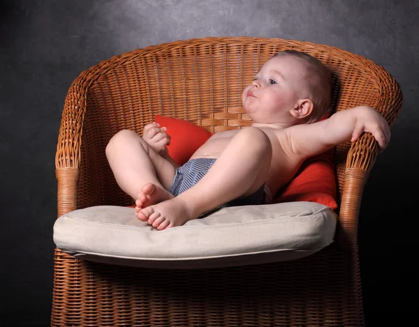O menino se senta em uma poltrona — Fotografia de Stock