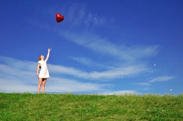 Flicka med en röd boll i form av hör — Stockfoto