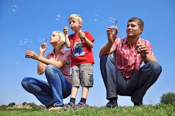 Happy family blowing soap bubbles — Stock Photo, Image