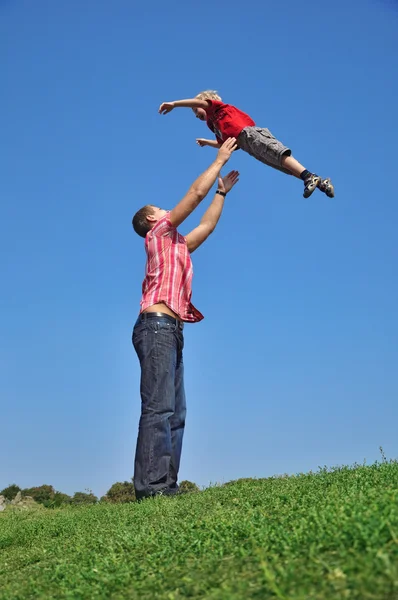 Father throwing his son in the air and c — Stock Photo, Image