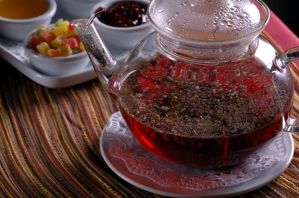 Glas Teekanne und Tasse mit Süßigkeiten — Stockfoto