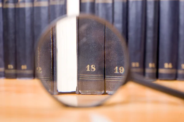 Close-up of magnifying glass with books — Stock Photo, Image