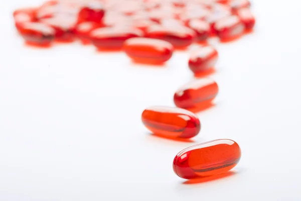 Красные таблетки на белом фоне — стоковое фото