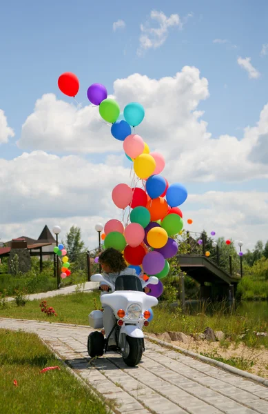 Little boy on motobike with helium bubbl — Stock Photo, Image