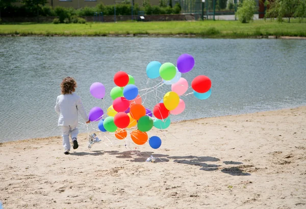 Маленький мальчик бегает с гелиевыми пузырьками на s — стоковое фото