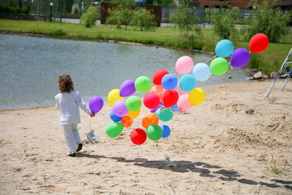 Little boy runs with helium ballons on s — Stock Photo, Image