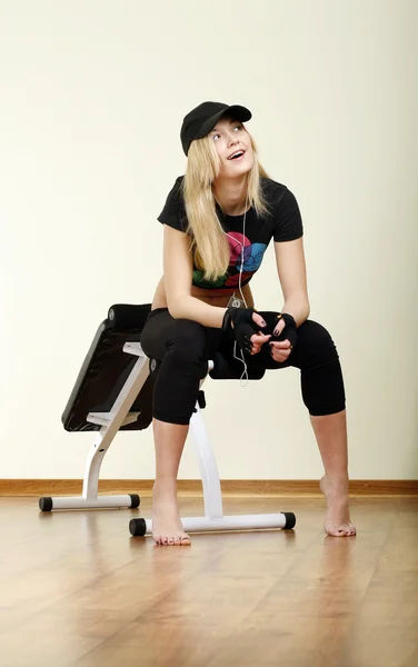 Girl sitting on fitness machine — Stock Photo, Image