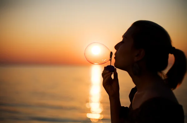 Meisje maken zeepbellen over zonsondergang — Stockfoto