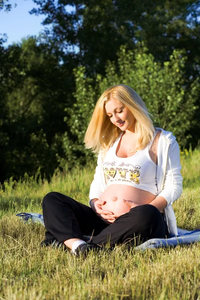 풀 위에 앉아 있는 임신부 — 스톡 사진