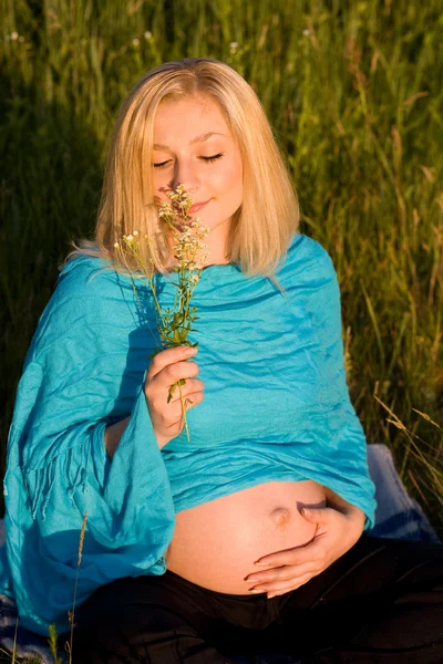 Těhotná žena sedí na trávě a s — Stock fotografie