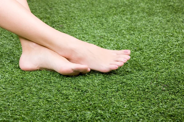 Belos pés femininos magros na grama — Fotografia de Stock