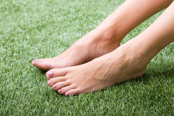 Beautiful slim female feet on grass — Stock Photo, Image