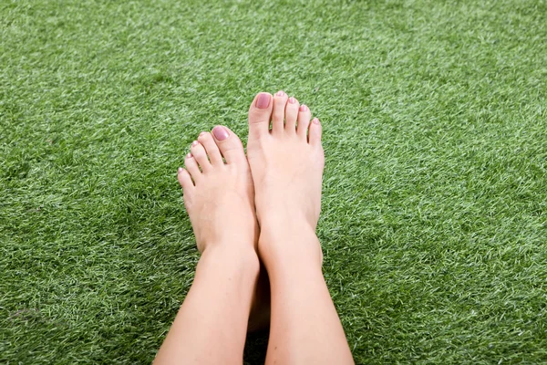 Beautiful slim female feet on grass — Stock Photo, Image