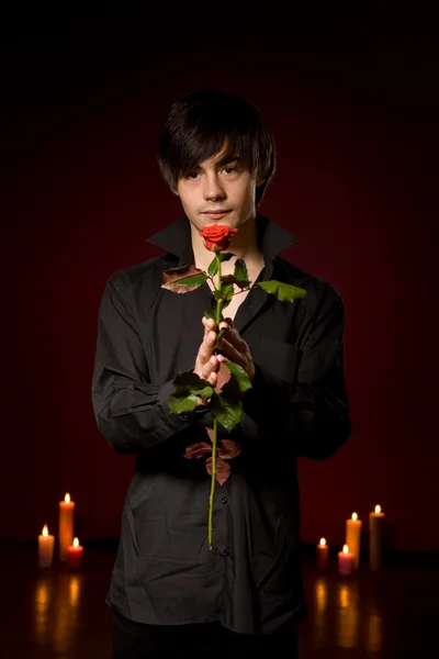 Νεαρός άνδρας με τριαντάφυλλο σε μαύρο πουκάμισο σε κόκκινο backg — Φωτογραφία Αρχείου