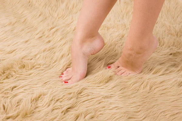 Belos pés femininos no tapete de lã — Fotografia de Stock