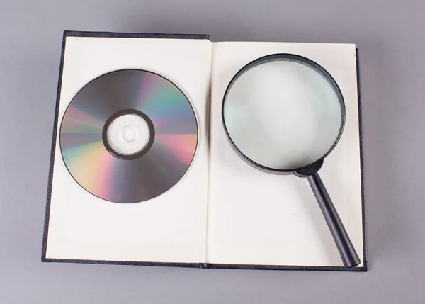 Libro aperto con lente d'ingrandimento e cd — Foto Stock
