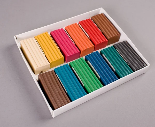 Разноцветный пластилин в коробке на сером — стоковое фото