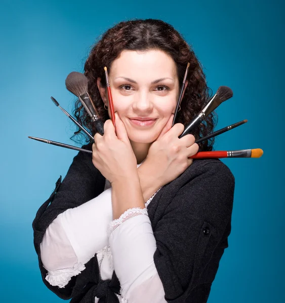 Stylist mit Make-up-Pinseln auf blauem Hintergrund — Stockfoto