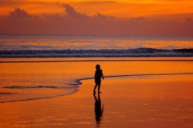 Boy on beach at sunset clipart