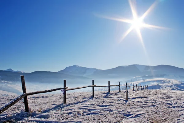 Wooden fence in snow covered mountains — Stock Photo, Image