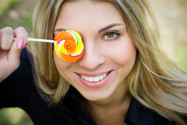 Žena s lollypop pokrývající její oko — Stock fotografie