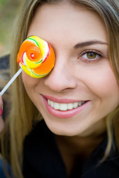 Žena s lollypop pokrývající její oko — Stock fotografie