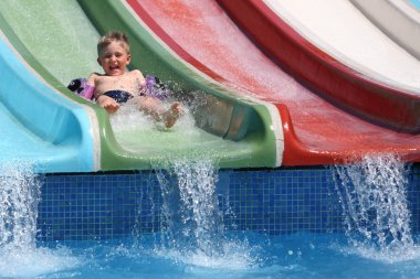 The boy slides a waterslide. clipart