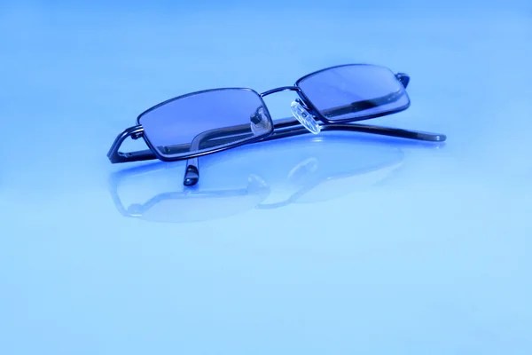 Γυαλιά απομονωμένη σε ένα ανοικτό μπλε υπόβαθρο και αντανάκλαση — Φωτογραφία Αρχείου