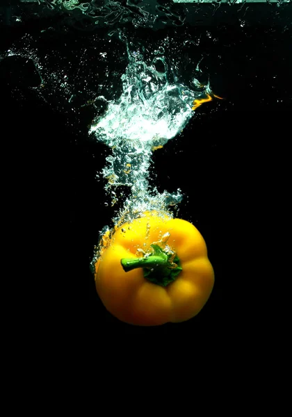 Gele peper in zwarte water — Stockfoto