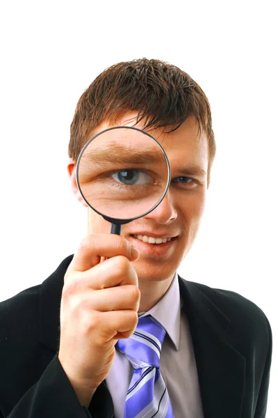 Young man looks through a magnifying glass — Stock Photo, Image
