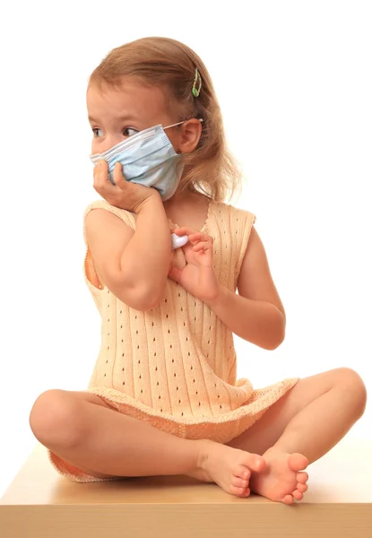 Menina está em uma máscara médica com um thermom — Fotografia de Stock