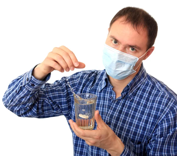 Homem em uma máscara médica dissolve uma pílula — Fotografia de Stock