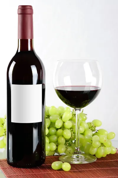 Garrafa e copo de vinho tinto e uvas — Fotografia de Stock
