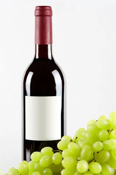 Flaska rött vin och gröna druvor i f — Stockfoto