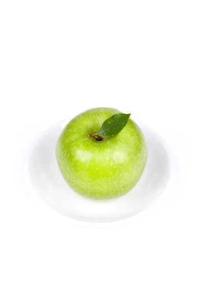 Una manzana verde madura con hoja en plato — Foto de Stock