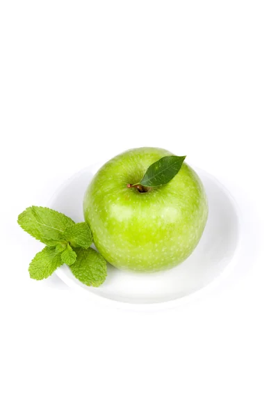Uma maçã verde madura com hortelã na placa — Fotografia de Stock