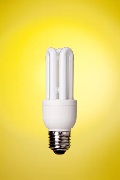Small energy saving lamp on yellow backg — Stock Photo, Image