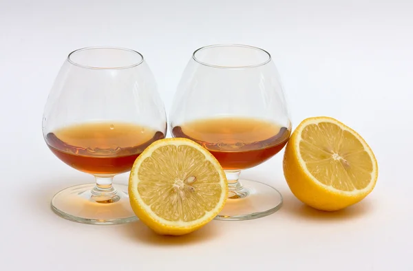 Two glasses of cognac and two halves of — Zdjęcie stockowe